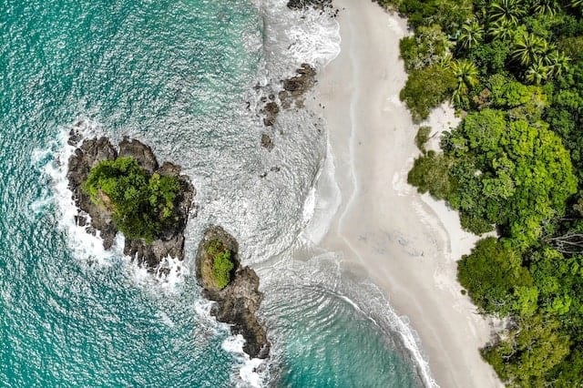 overhead view of a white sand beach thats secluded in manuel antonio in costa rica