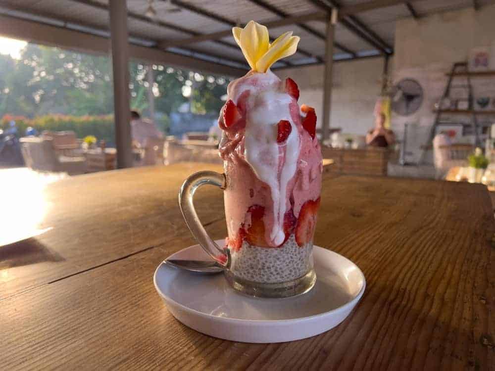 massive vegan strawberry shake overflowing from a glass mug at a cafe in bali