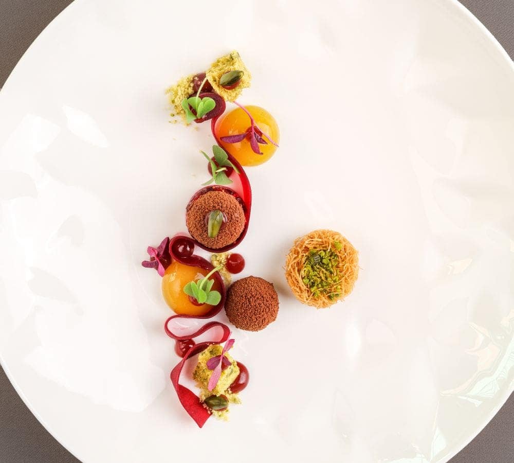 beautifully plated fruit and vegetable dish on a white plate at a michelin starred restaurant