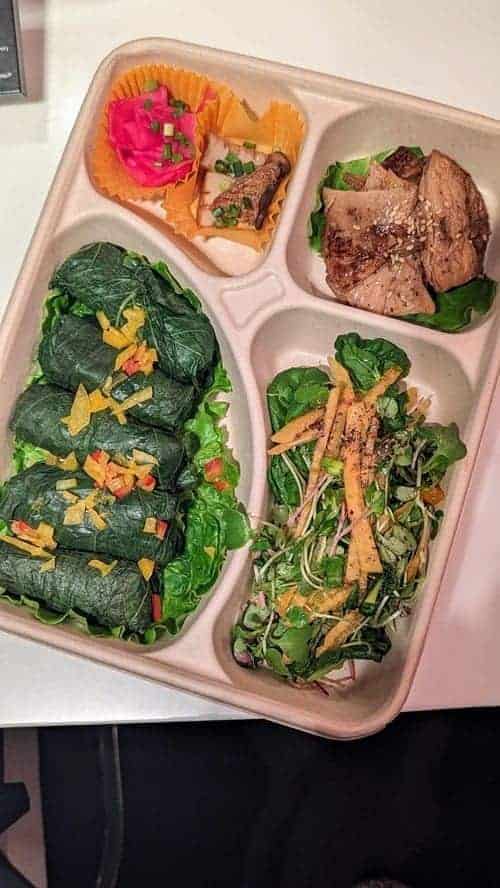 vegan lunch box with small cabbage rolls, mushroom salad, tofu and pickled veggies from lovinghut land in seoul