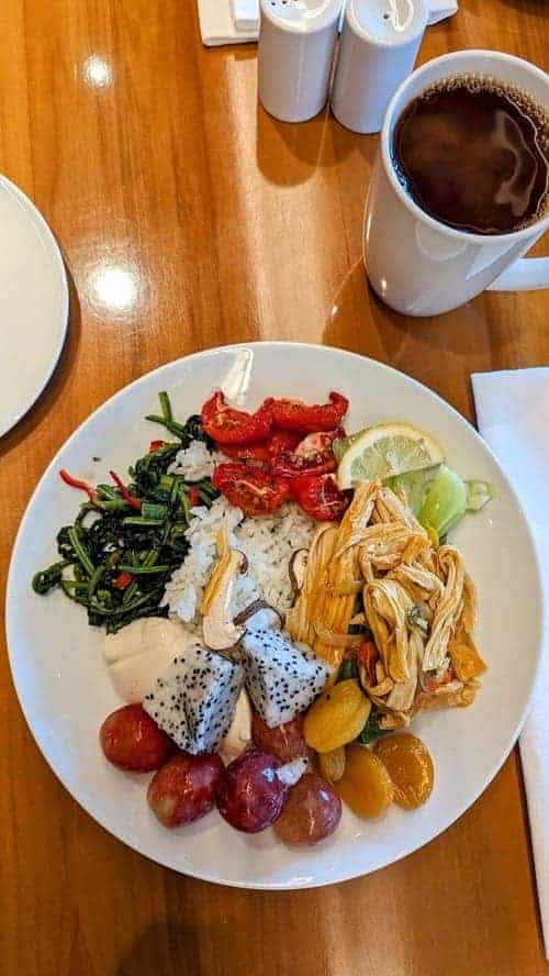 a mixed plate of vegan western and korean breakfast foods next to a coffee at the plaza hotel in seoul