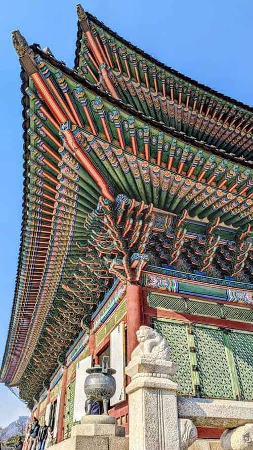 the colorful roof of the  Gyeongbokgung palace flanked by stone lions in seoul