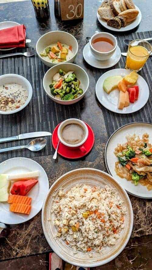 vegan breakfast spread with fried rice, stir fried veggies, granola, fruit and coffee at the so bangkok hotel