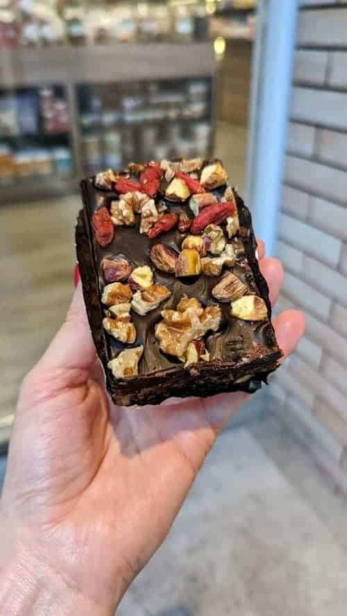 a raw, vegan, gluten free chocolate bar topped with nuts and goji berries held outside of the sunshine market in bangkok