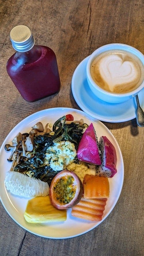 vegan breakfast spread with fresh juice, fruit, tofu scramble, and a latte with a heart at the kimpton mai laa