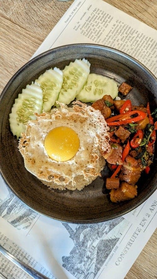 vegan pork with a fried vegan egg on top in a black bowl at vegano bistro in chiang mai