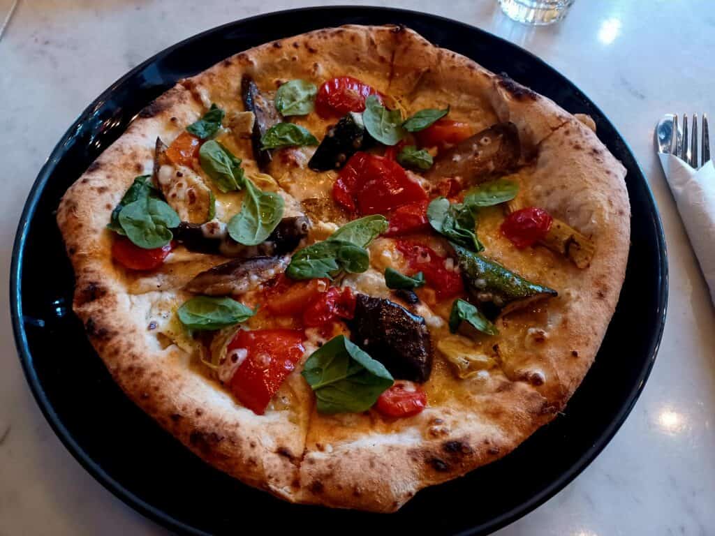 a small round vegan pizza on a black plate at trattoria vesso in halifax