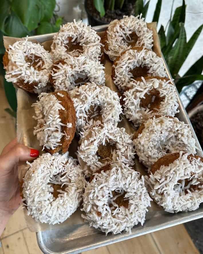 a tray of vegan cake donuts covered in coconut frosting at clementine bakery in brooklyn, nyc