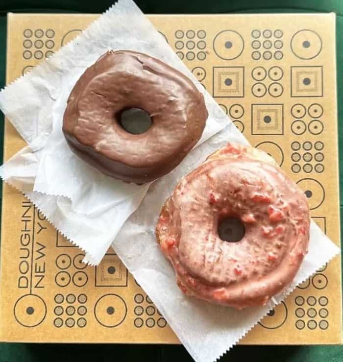 two vegan glazed donuts side by side on a piece of wax paper at doughnut plant in nyc