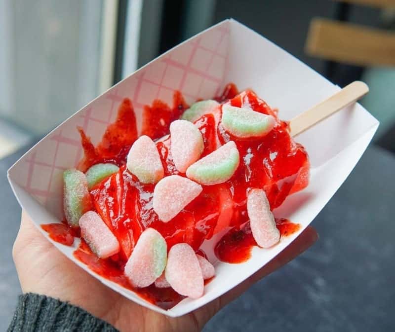 a vegan strawberry paleta topped with strawberry sauce and gummy candy from ice queen in portland