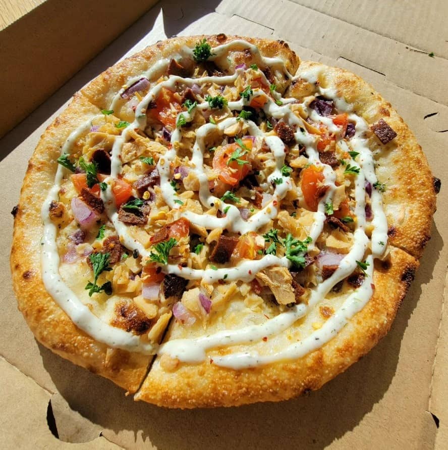 a small round vegan buffalo chick'n pizza topped with a drizzle of ranch dressing at vegan van in denver