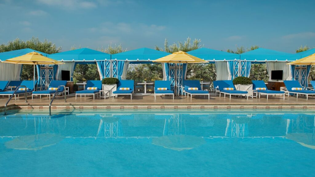 outdoor pool area with yellow and teal umbrella chairs around the perimeter in beverly hills
