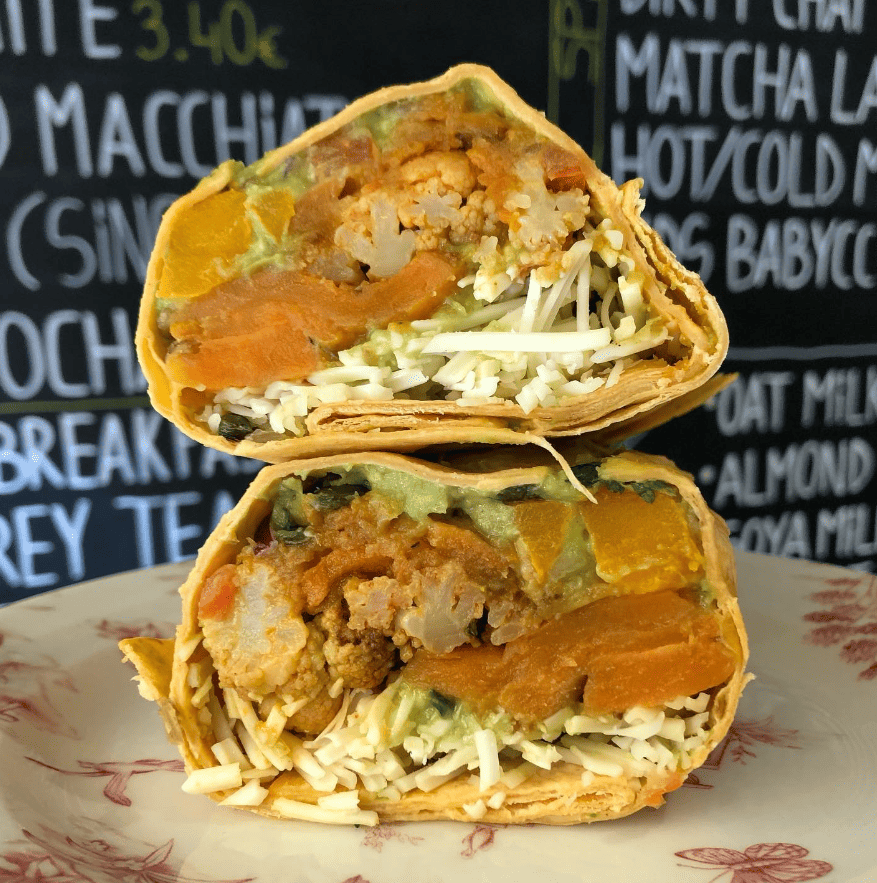 an upclose shot of a vegan burrito cut in half exposing the veggie meat, cheese, lettuce, and more at roco cafe in dublin