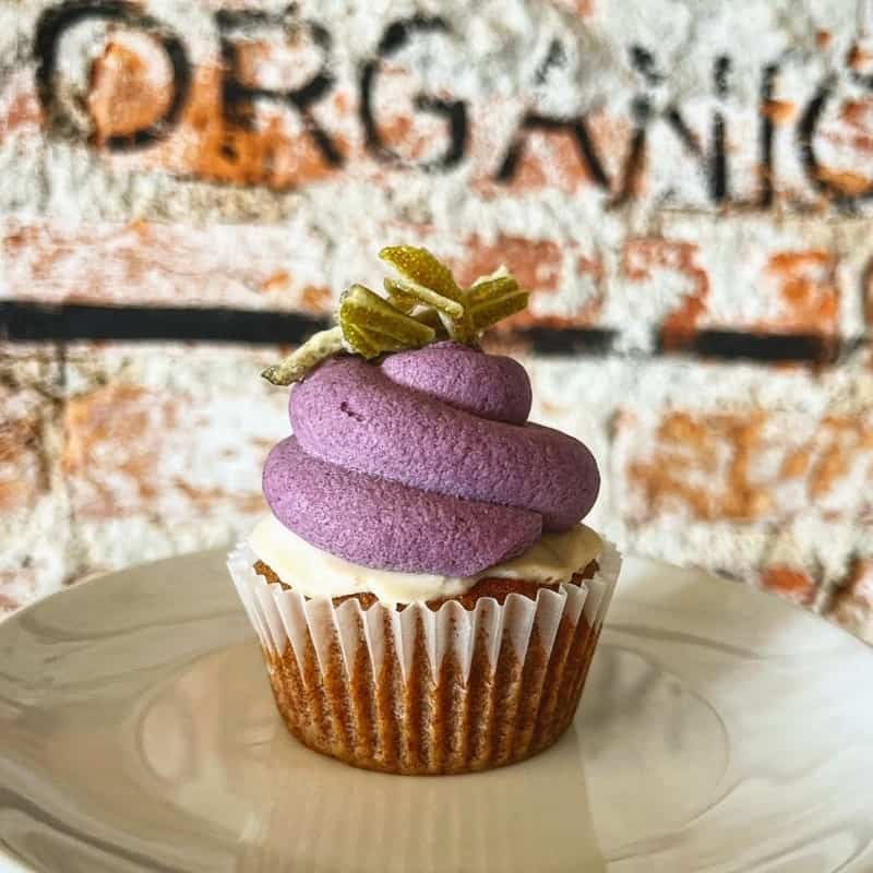 vegan and gluten free cupcake sitting on a plate topped with a swirl of purple buttercream at ps and co in philadelphia