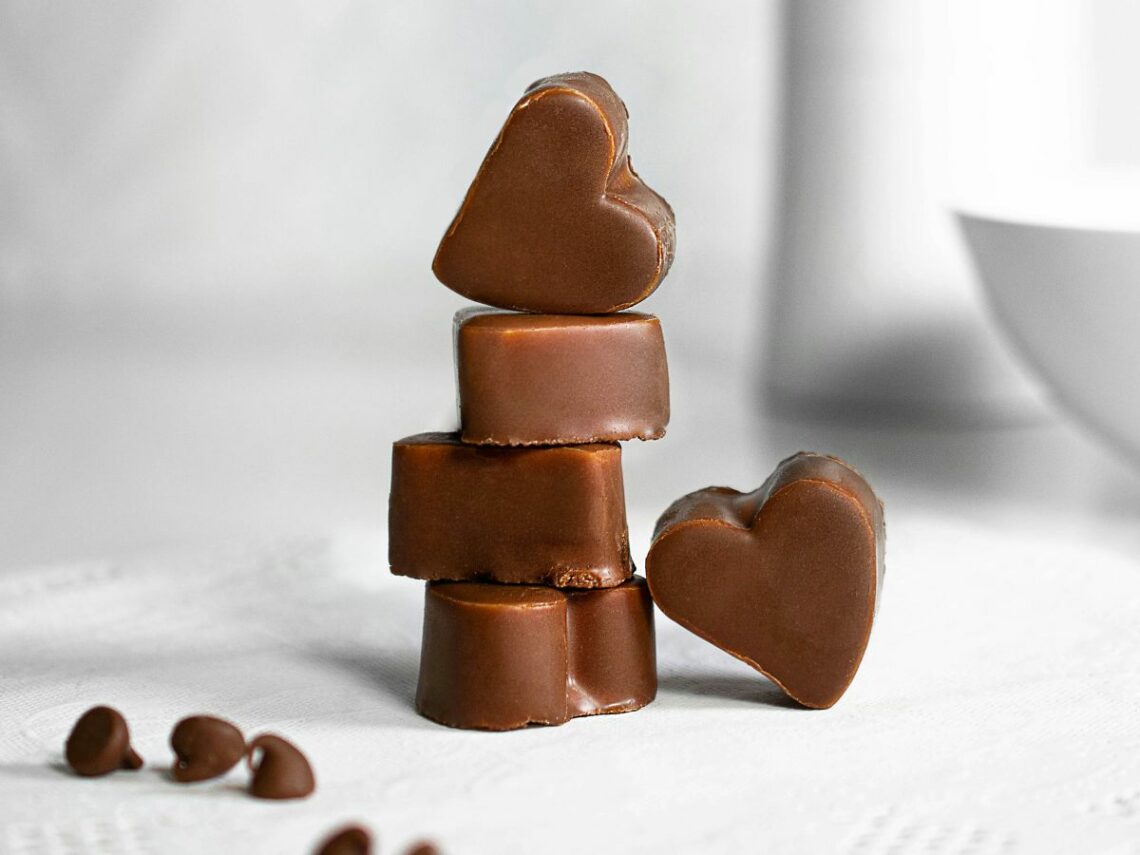 a stack of small vegan chocolate hearts on a white counter with a white background