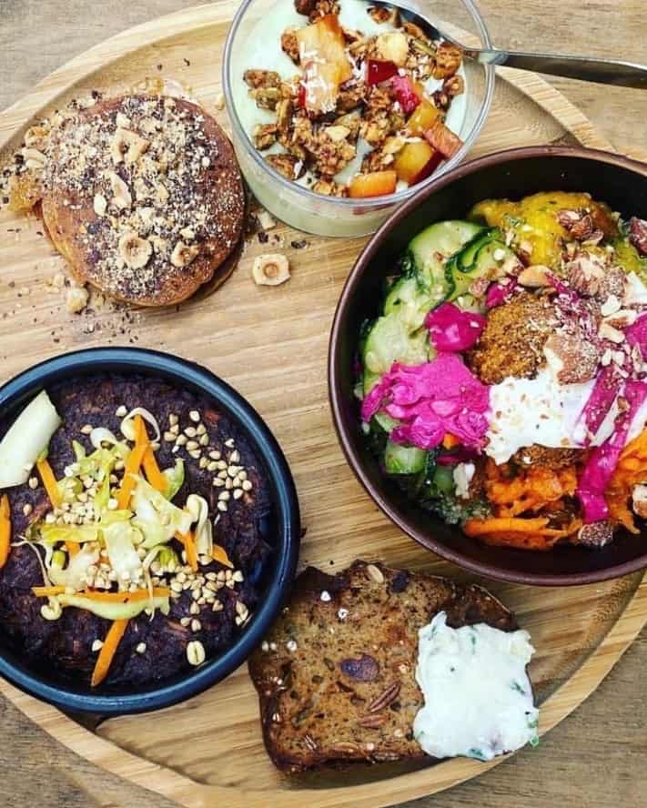 vegan yogurt bowl, sweet breads, and a scramble spread out on a wood tray at Les bols d'Antoine in paris for breakfast
