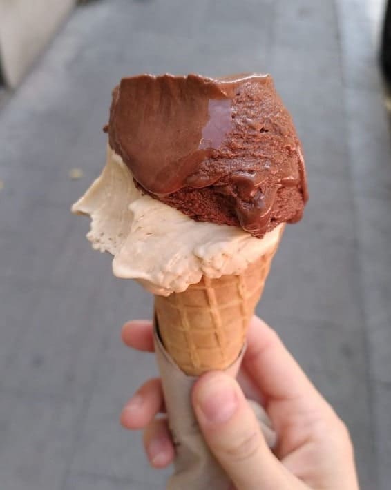 an ice cream cone topped with two scoops of vegan gelato and held with one hand in barcelona