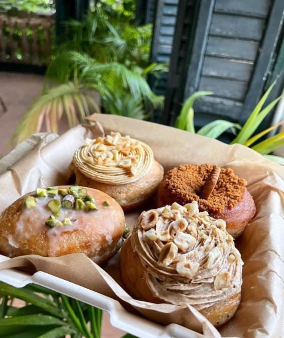 a box of four golden vegan donuts topped with sugar and butter cream from areca bakery in barcelona