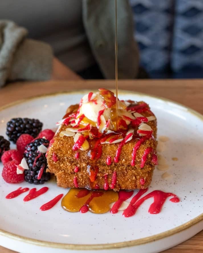 a thick cut slice of vegan french toast covered in a crispy breading and drizzled with raspberry sauce at fresh kitchen in toronto