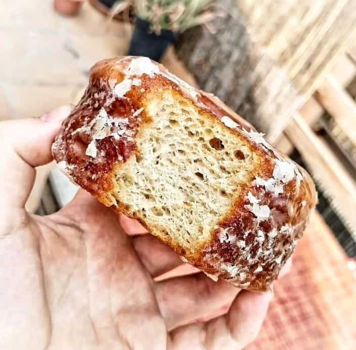 a light and flaky vegan and gluten free cronut with a bite taken out of it to expose the flaky layers at hanai vegana barcelona
