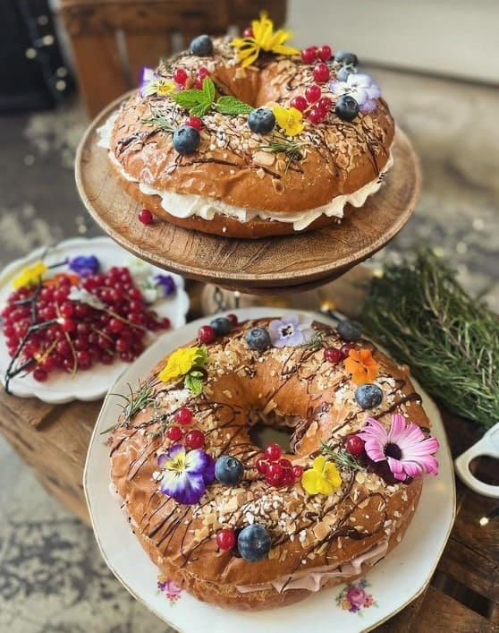 two beautiful round vegan caked topped with sugar and colorful flowers sitting on cake stands at la besneta in barcelona