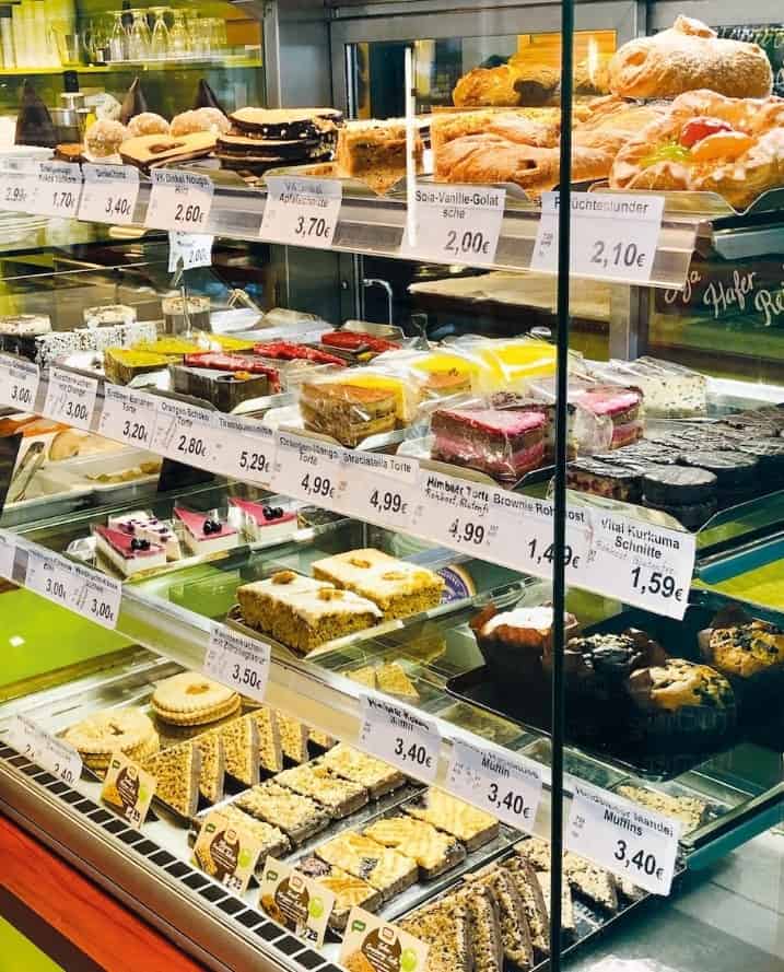 a dessert case filled with individual vegan cakes, cookies, pastries, and desserts at the vegan supermarket maranvegan in vienna