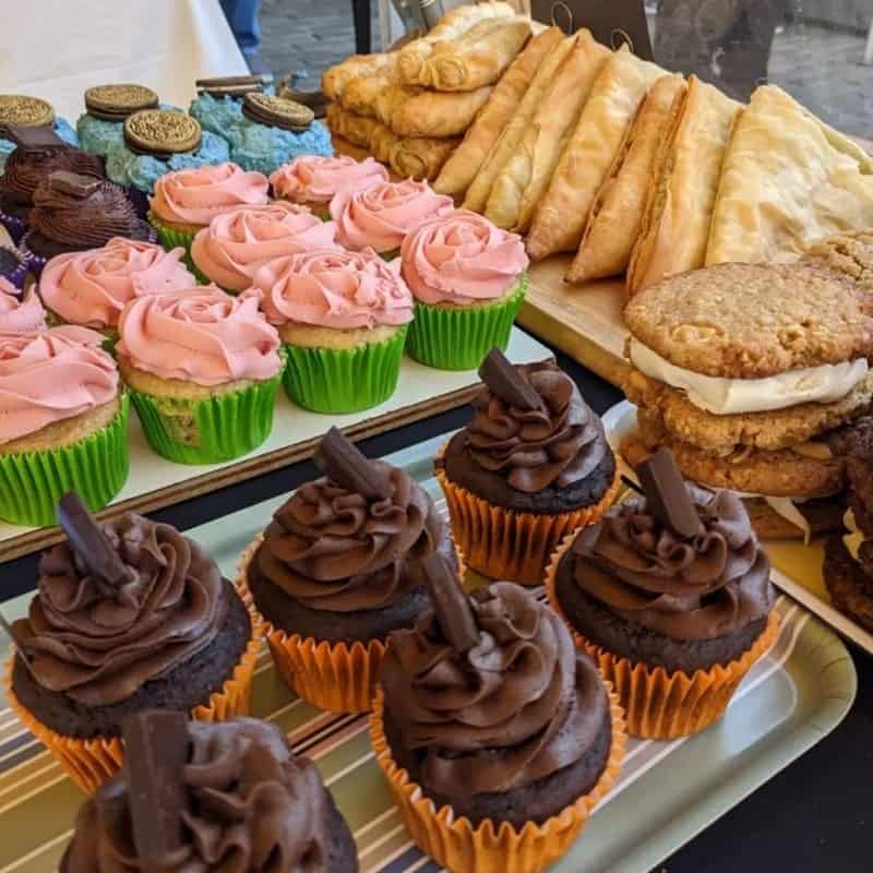 rows of vegan chocolate and vanilla cupcakes topped with swirls of chocolate and strawberry frosting next to pastries at missy cupcakes in edinburgh