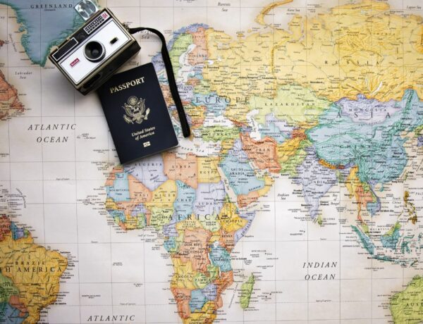 a camera and a passport sitting on top of a colorful world map