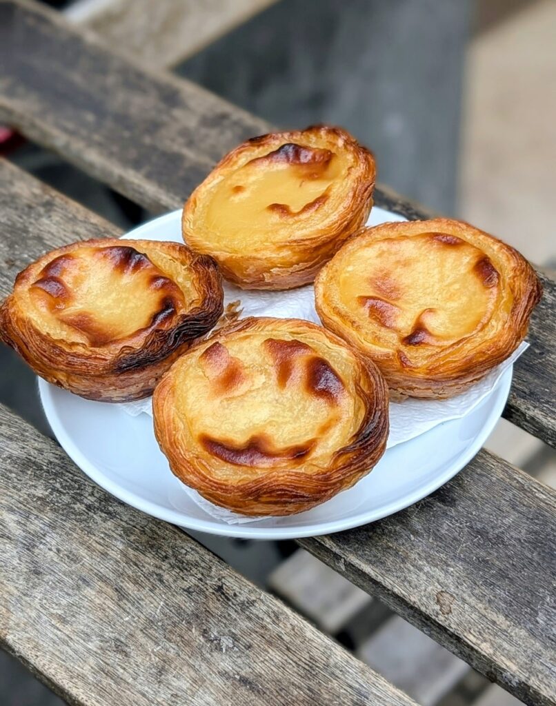 a small round plate with four vegan pasteis de nata in lisbon