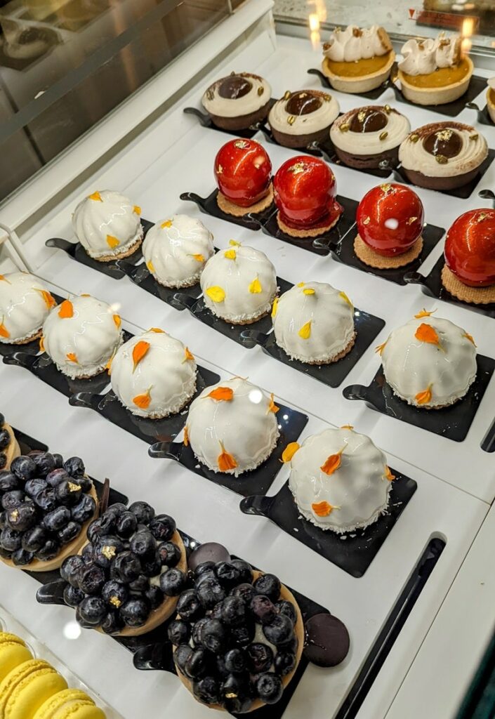 rows of colorful vegan pastries inside of a dessert case at the vegan french bakery l'artisane in miami