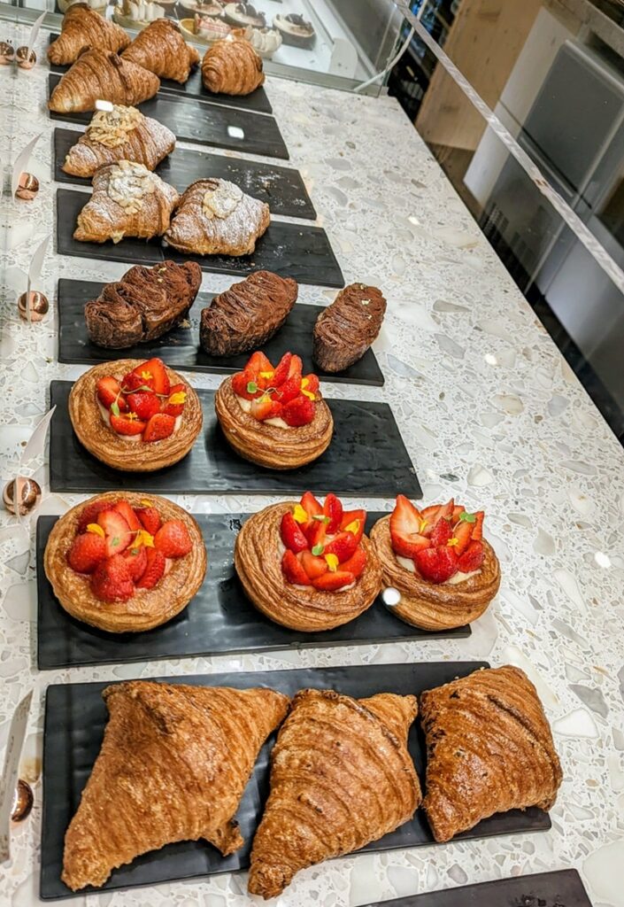 rows of golden vegan croissants and pastries inside of a dessert case at the vegan french bakery l'artisane in miami