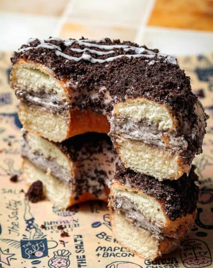 a vegan oreo cookie donut topped with chocolate cut in half revealing more chocolate and cream inside from the salty donut bakery in miami