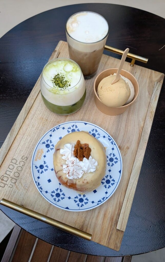 a wood serving tray with a vegan banoffe donut next to a matcha and a scoop of icecream at scoop n dough