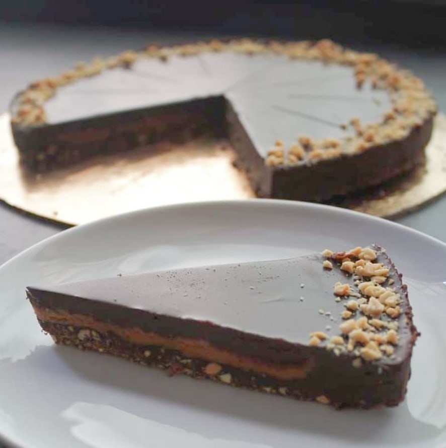 a slice of vegan chocolate tart on a plate in front of a larger tart at a vegan bakery in lisbon