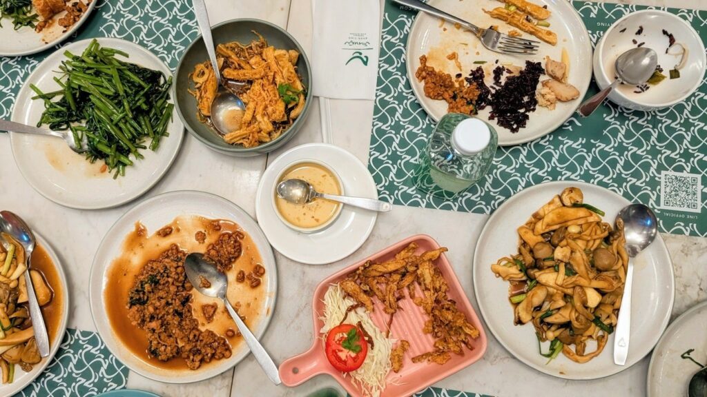 table covered with a mix of vegan thai dishes, some half eaten at Baan Ying Plant-Based in bangkok