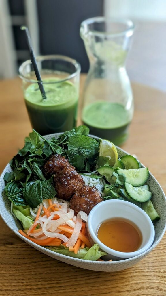 a japanese inspired vegan veggie bowl with three savory soy buns next to a large green juice at avocado in athens