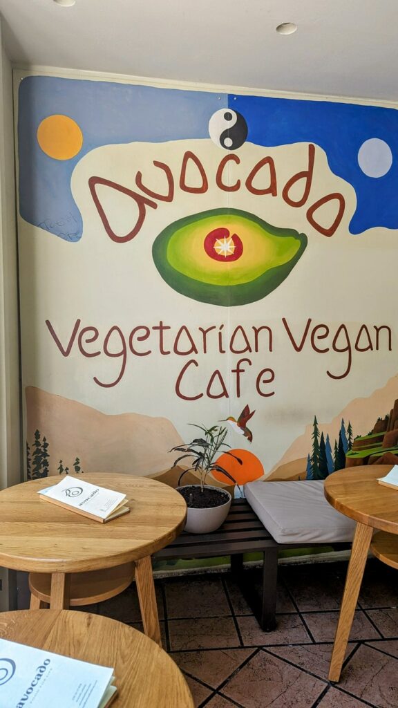 the colorful restaurant welcome sign with a big green avocado for avocado vegetarian and vegan cafe in athens