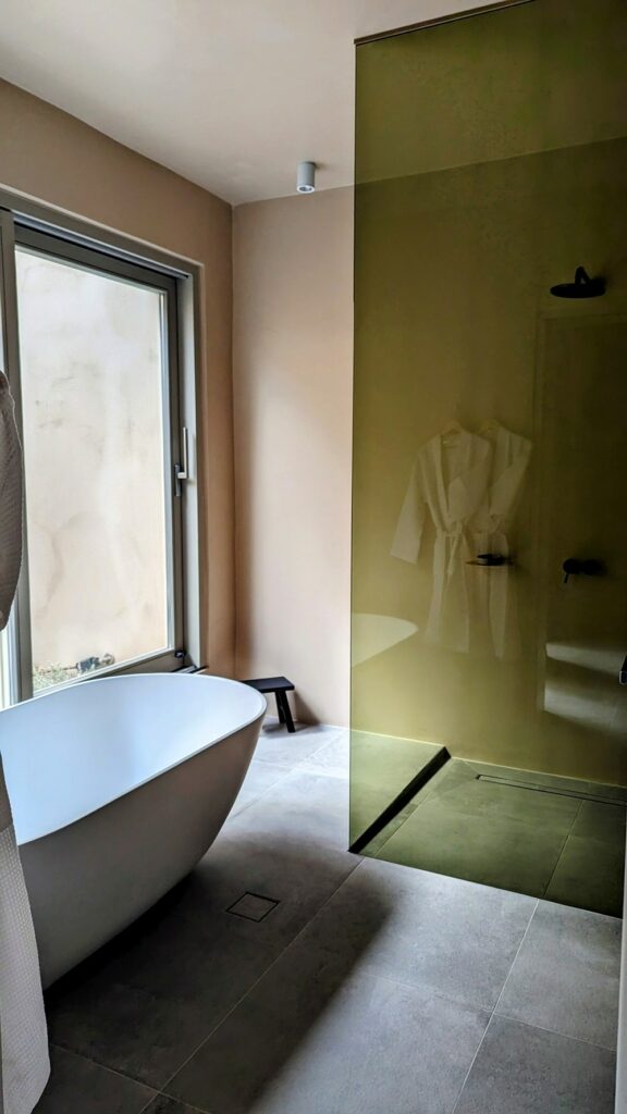 large bathroom with a soaking tub and walk in shower at ethos vegan retreat in santorini