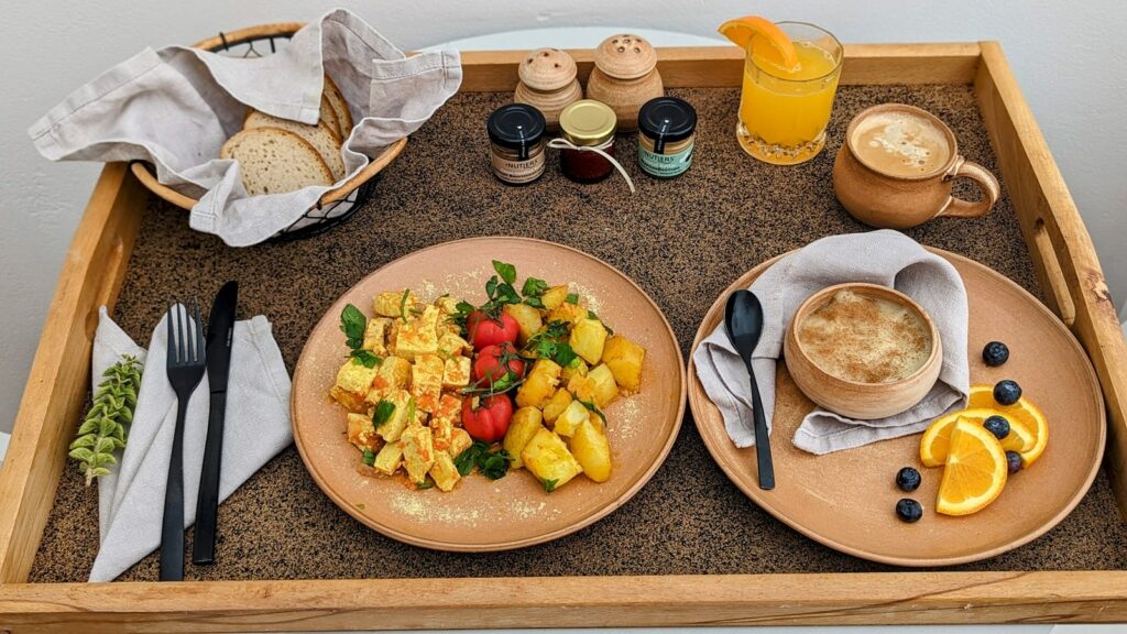 vegan breakfast platter with scrambled tofu, rice pudding, potatoes and fresh juice at ethos suites in fira santorini 