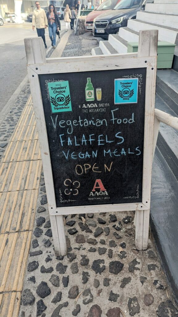 a small chalk board sign that says vegetarian food and falafel for falafeland in santorini