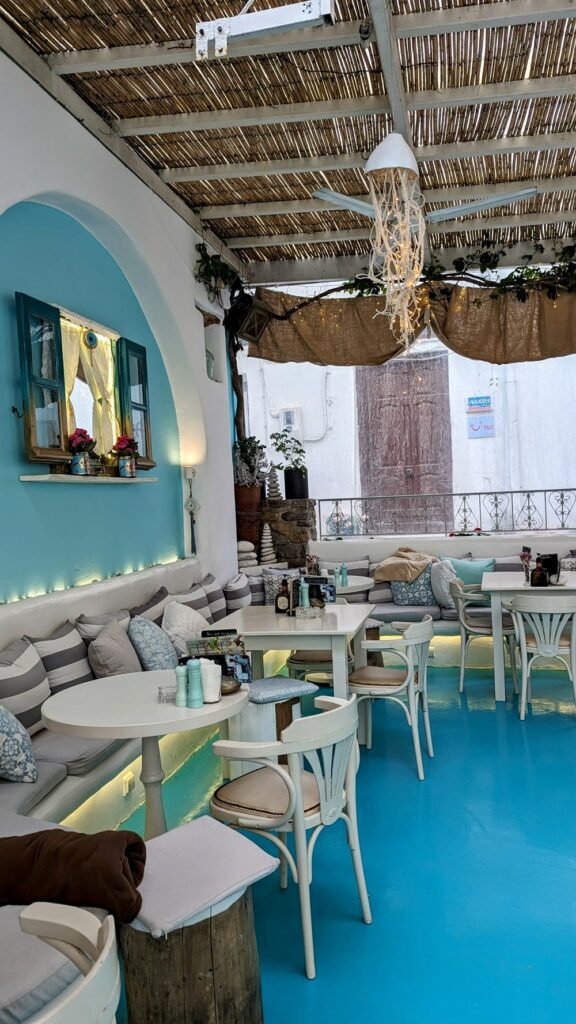 inside of the beachy themed dining space with white tables and blue walls at gemma naxian  in naxos