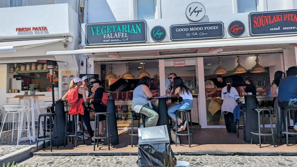 the storefronts for good mood food and vegetarian falafel in fira's main square in santorini