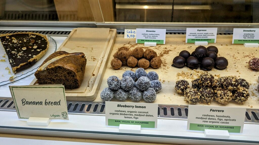 a dessert case filled with vegan energy balls, bread, a chocolate tart at happy blender in athens greece