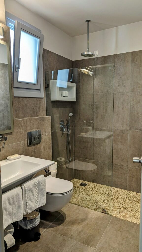 a medium sized, modern bathroom with a rainfall shower head at hotel grotta in naxos