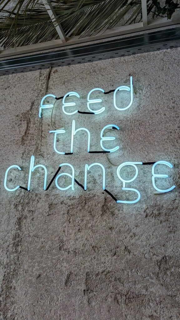 a neon sign that says feed the change at mother bistro in athens greece