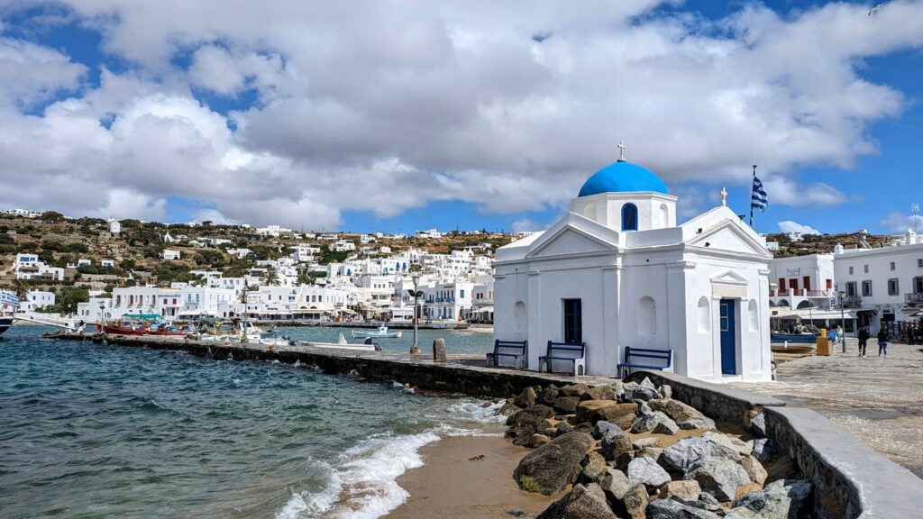 partial view of the mykonos harbor and white washed town in a sunny day