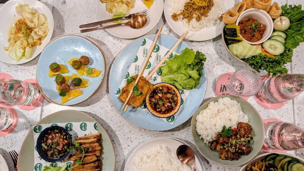 a large spread of vegan thai dishes over a long table at natures charm in bangkok