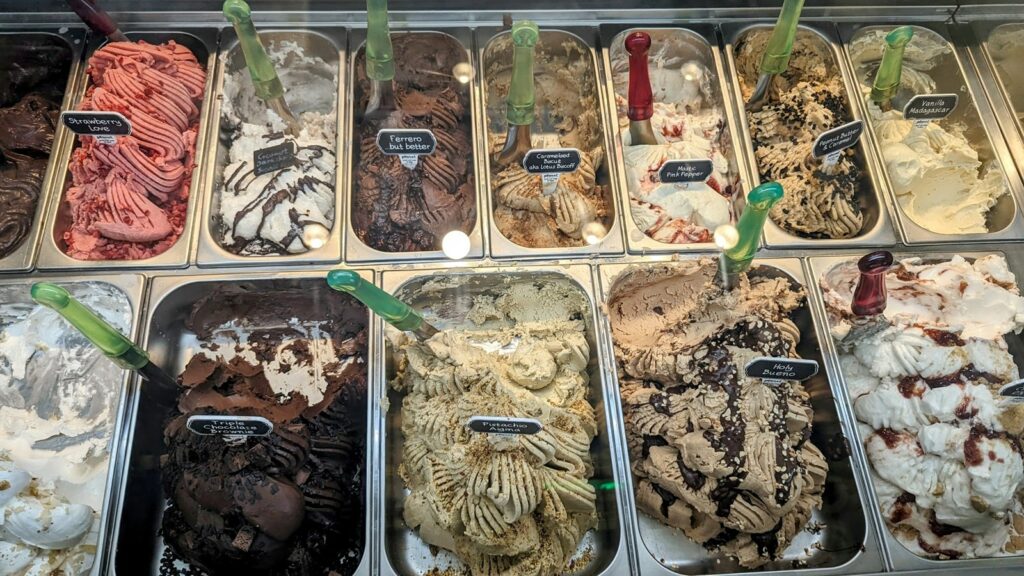 ten silver ice cream trays filled with colorful vegan ice creams like strawberry and chocolate in athens
