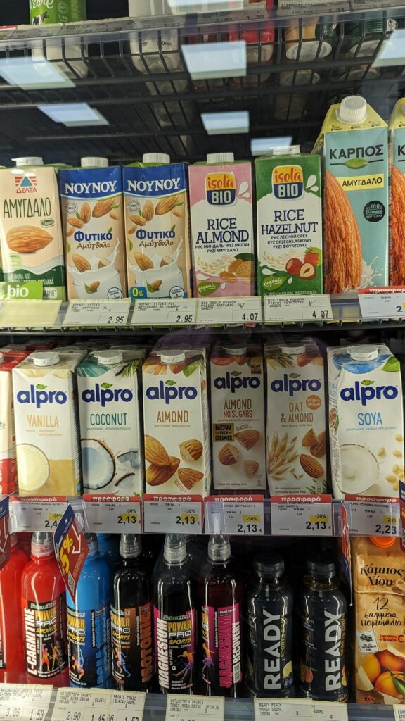 rows of vegan non dairy milk containers inside of a fridge at a supermarket in naxos