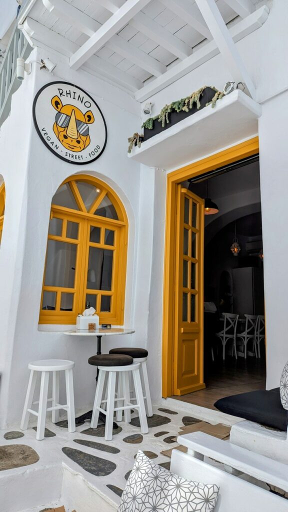 the white and yellow entrance to the vegan restaurant rhino vegan street food in mykonos 